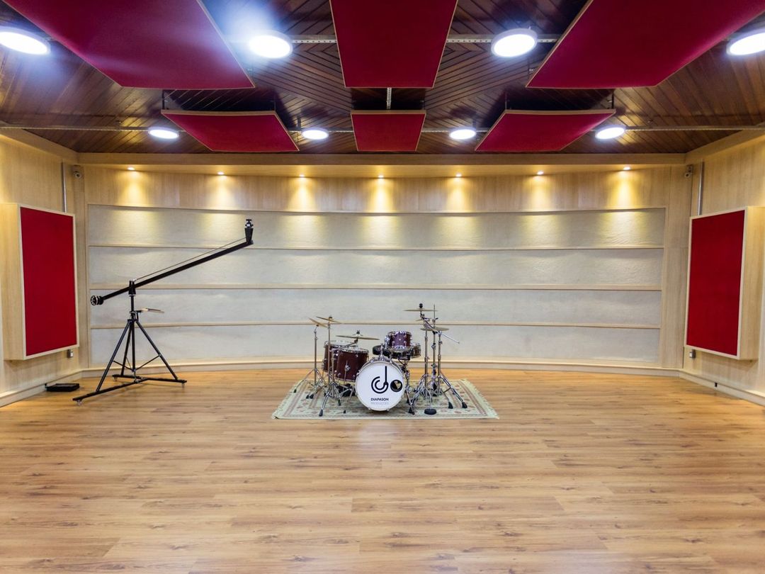 Sala de gravação do Estúdio A, com painéis acústicos e luz quente