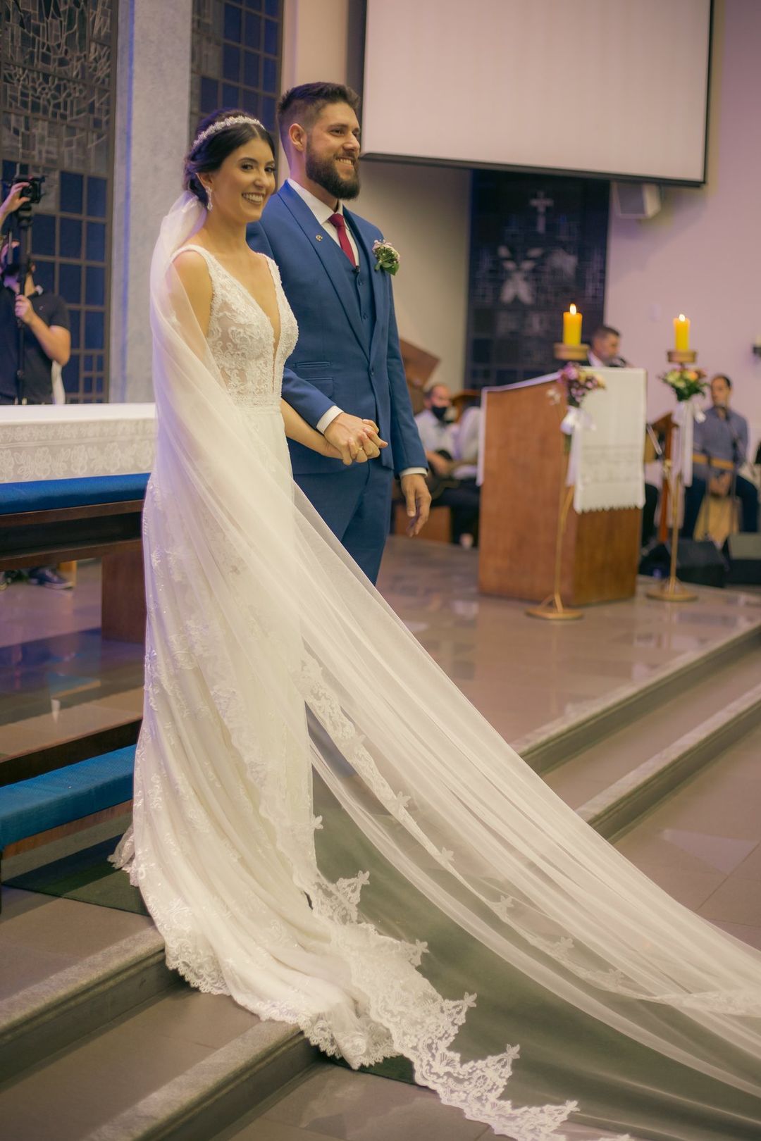 Noivos no altar da igreja, com o véu longo da noiva sobre a escada